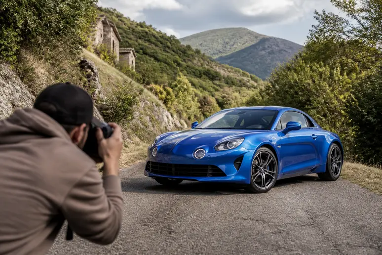 Un photographe automobile capture la beauté d'une Alpine A110 sur une route pittoresque française.