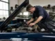 Un mécanicien examine le compartiment moteur d'une bentley occasion dans un atelier spécialisé.