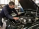 Mécanicien inspectant le moteur d'une jaguar mk2 classique dans un atelier de restauration automobile