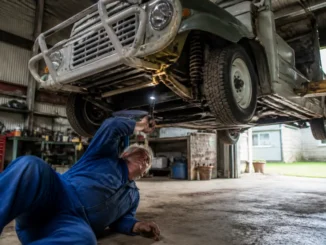 Un mécanicien inspecte le châssis d'une mini moke occasion dans un atelier de restauration automobile