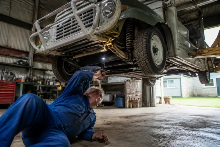 Un mécanicien inspecte le châssis d'une mini moke occasion dans un atelier de restauration automobile