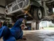 Un mécanicien inspecte le châssis d'une mini moke occasion dans un atelier de restauration automobile