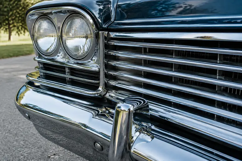 Gros plan sur le pare-chocs chromé et la calandre d'une cadillac vintage restaurée.