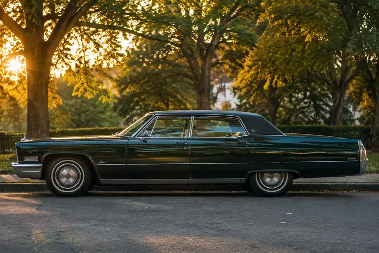 Berline cadillac vintage stationnée le long d'une rue arborée en lumière naturelle.