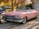 Un mécanicien inspecte une magnifique cadillac vintage décapotable garée dans une allée ensoleillée