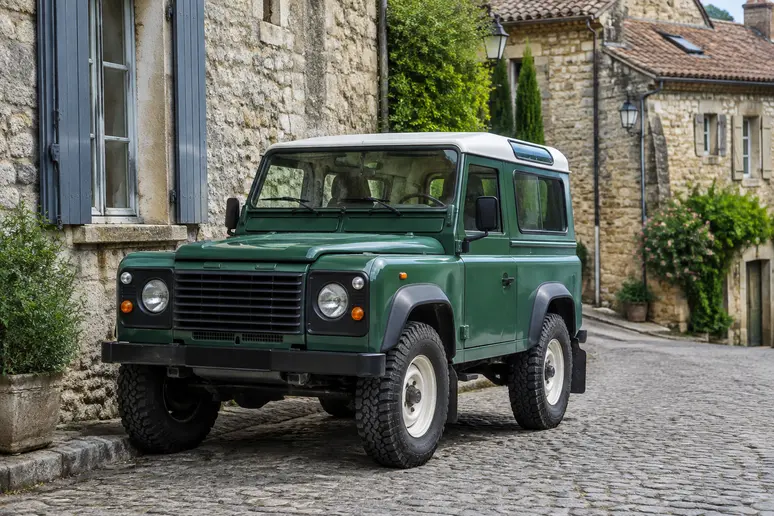 Defender vintage modèle 90 à empattement court stationné dans une rue pavée de village