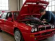 Un mécanicien inspecte le compartiment moteur d'une lancia delta integrale evo 2 dans un garage lumineux
