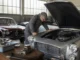 Un mécanicien examine le compartiment moteur d'une lancia flaminia dans un atelier de restauration.