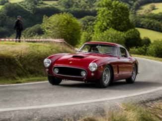Une voiture de collection participe au tour auto 2026 parcours sur une route sinueuse.