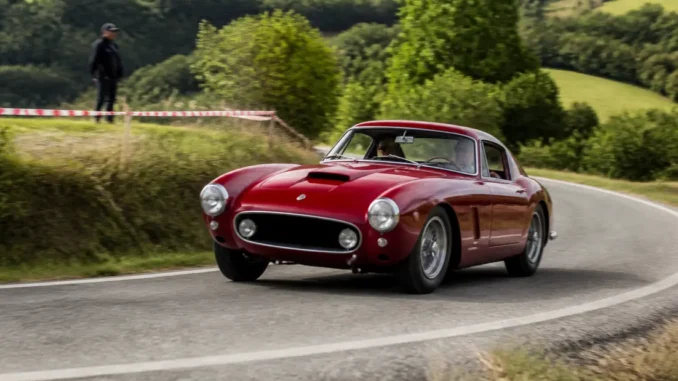 Une voiture de collection participe au tour auto 2026 parcours sur une route sinueuse.