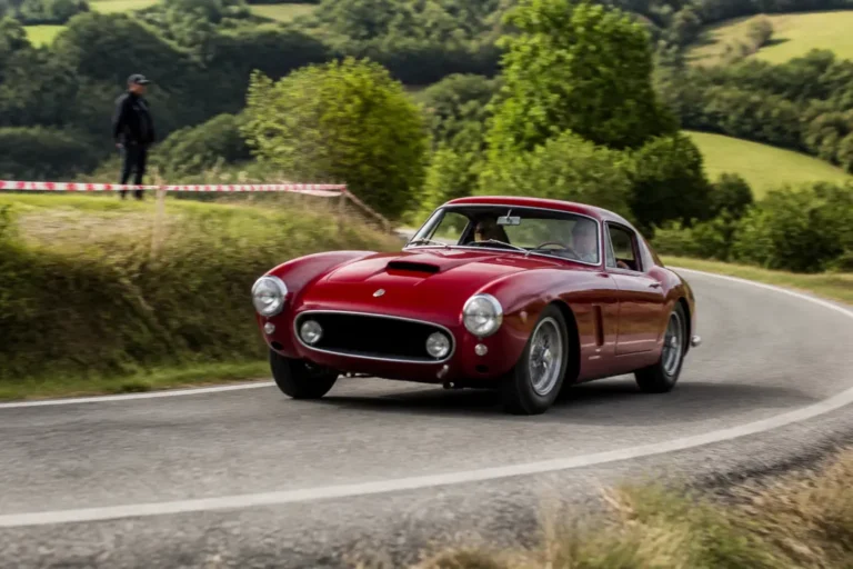 Une voiture de collection participe au tour auto 2026 parcours sur une route sinueuse.