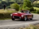 Une voiture de collection participe au tour auto 2026 parcours sur une route sinueuse.