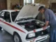 Un expert examine le moteur d'une voiture ancienne lors de l'évaluation d'une visa chrono occasion en atelier.