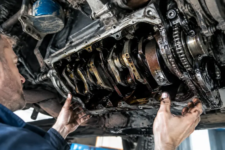 Mécanicien inspectant le bas moteur d'une voiture de collection pour détecter une usure de bielle