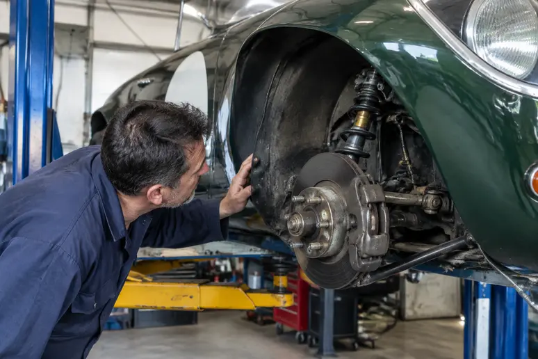 Un expert inspecte le châssis d'une voiture de course ancienne pour repérer d'éventuelles traces de rouille.